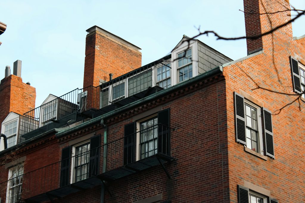 Charming historic brick building with black shutters and chimneys in Boston, Massachusetts.